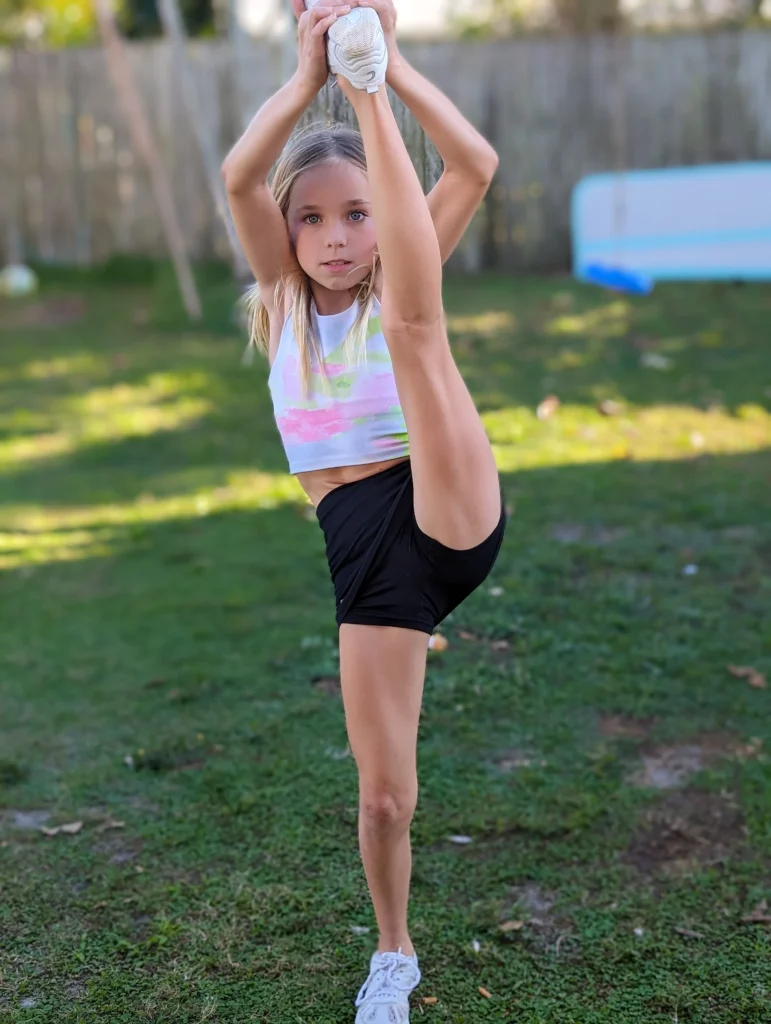 Younger Kinsley holding a heel stretch on the lawn