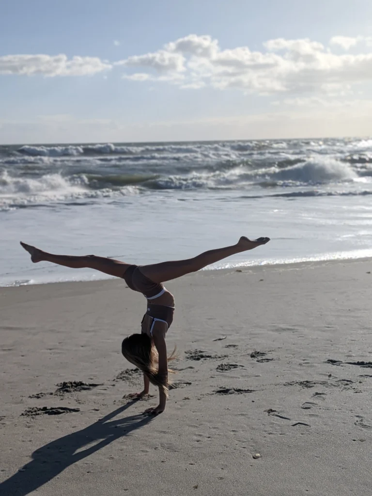 Kinsley doing a handstand split on the beach