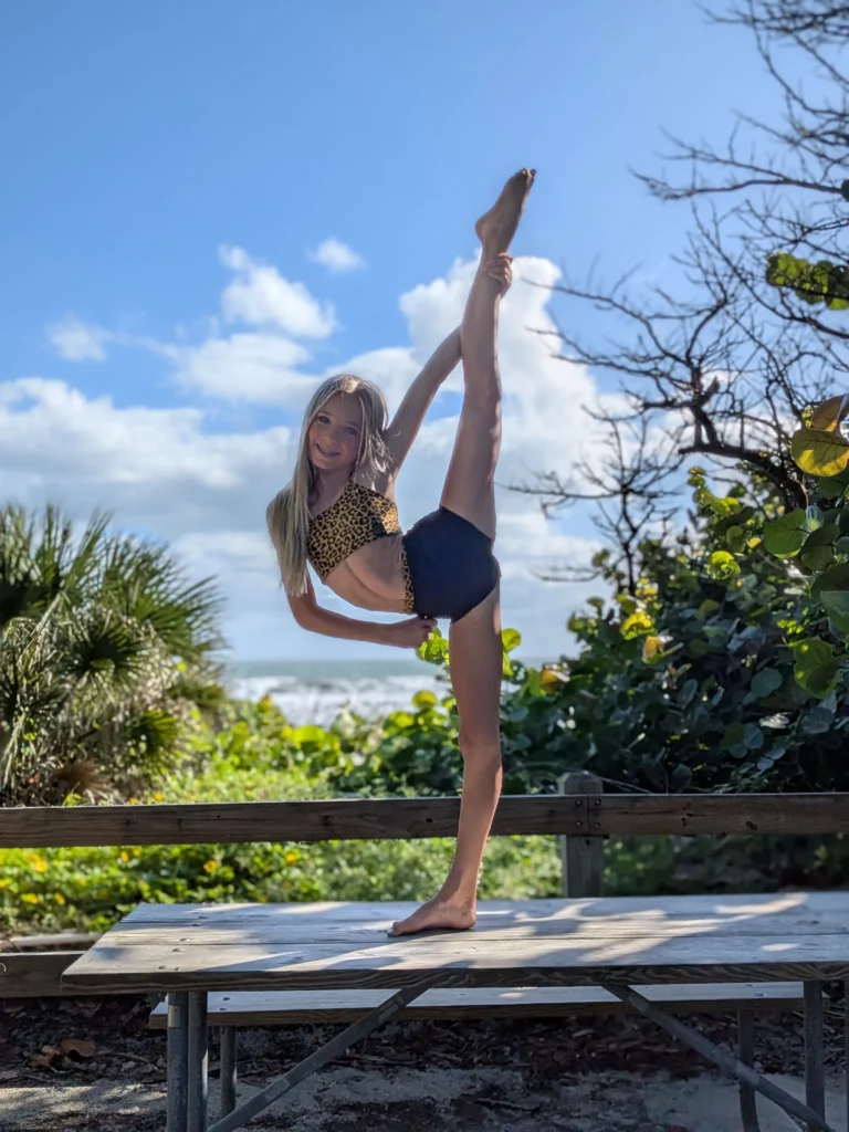 Kinsley holding a heel stretch on a picnic table by the dunes