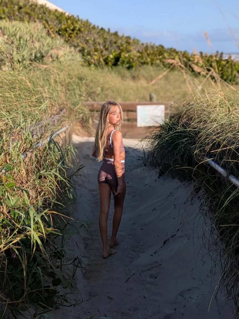 Kinsley looking back over her shoulder on a sandy dune path
